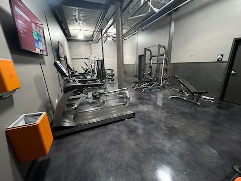 gym filled with lots of exercise equipment and a ceiling fan .