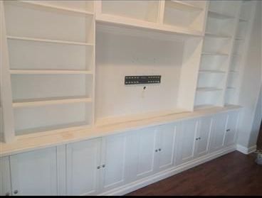 An empty room with a ladder and paint buckets on the floor.