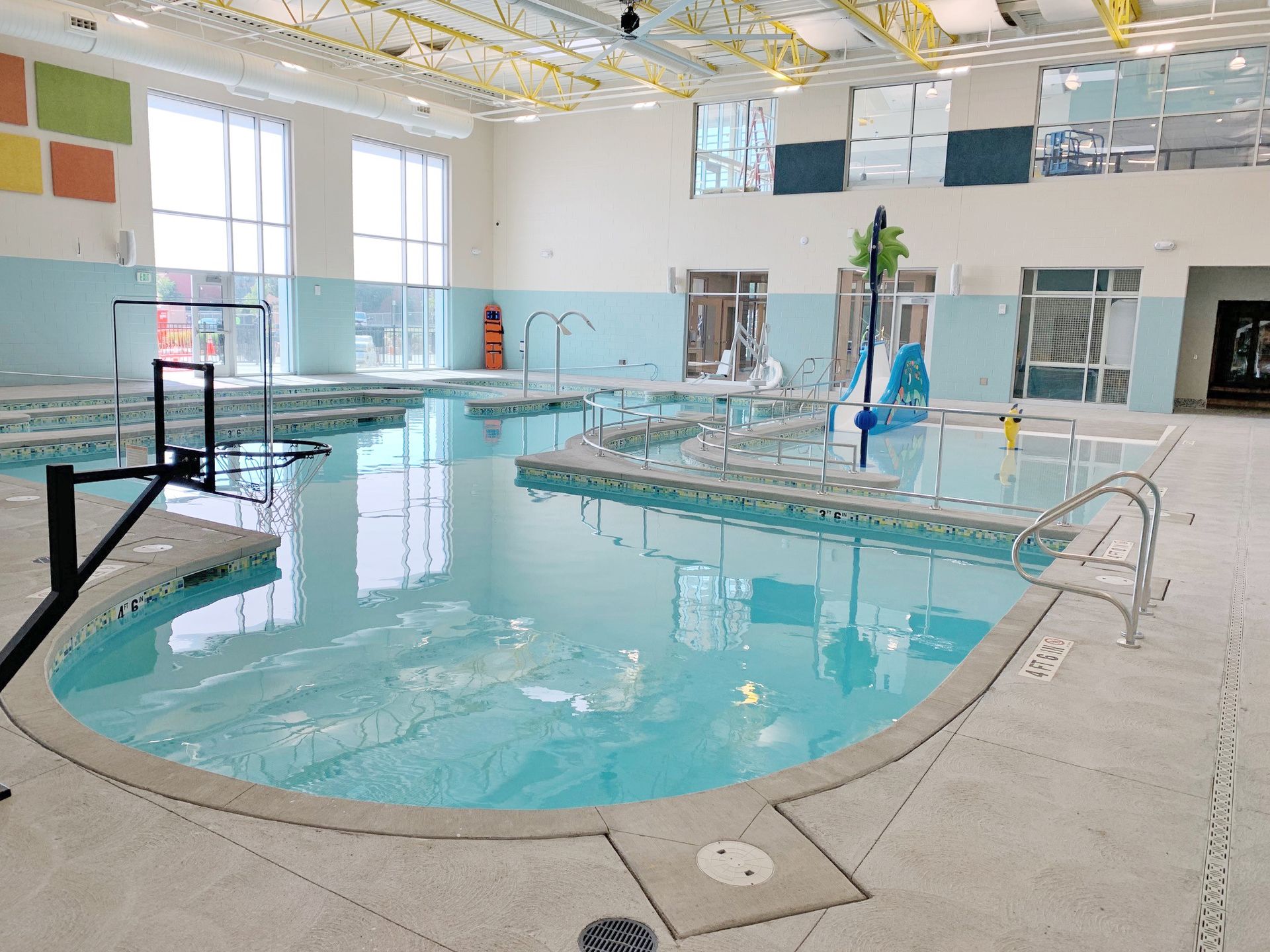 Indoor swimming pool with ramps and handrails for accessibility.
