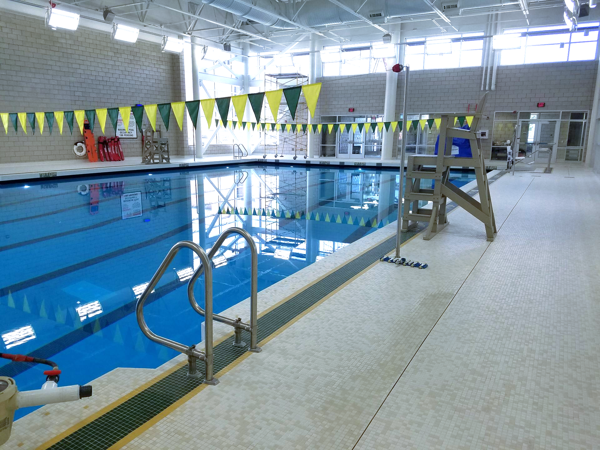 Indoor swimming pool with blue water, lanes marked, and lifeguard chair.