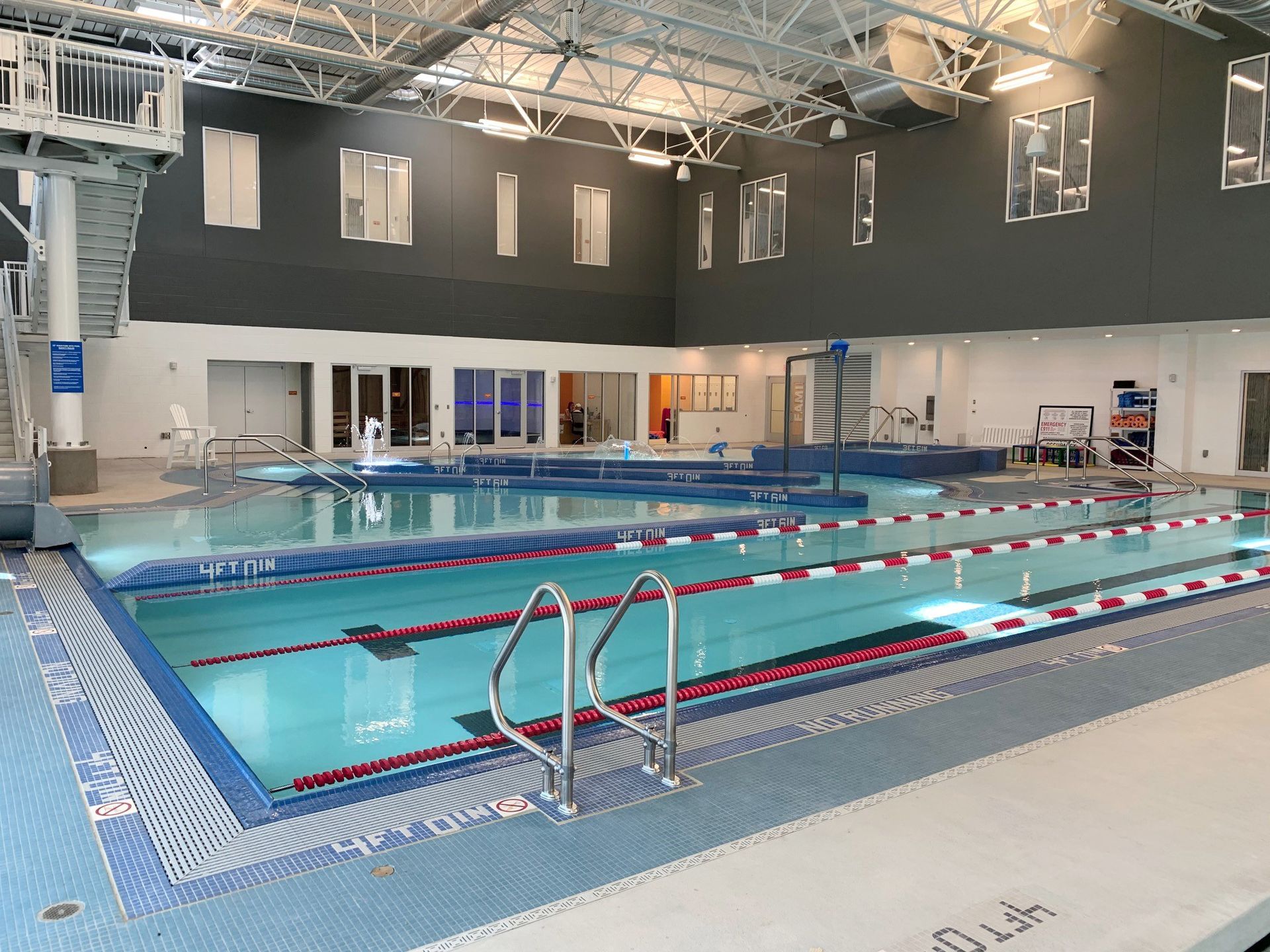 Indoor swimming pool with lanes, a diving board, and blue water.