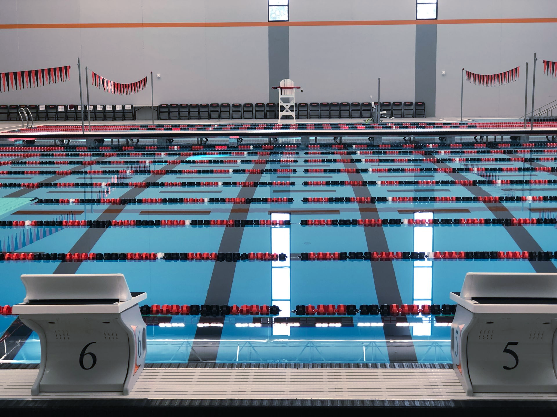 Empty indoor swimming pool with lanes marked, two starting blocks in foreground.