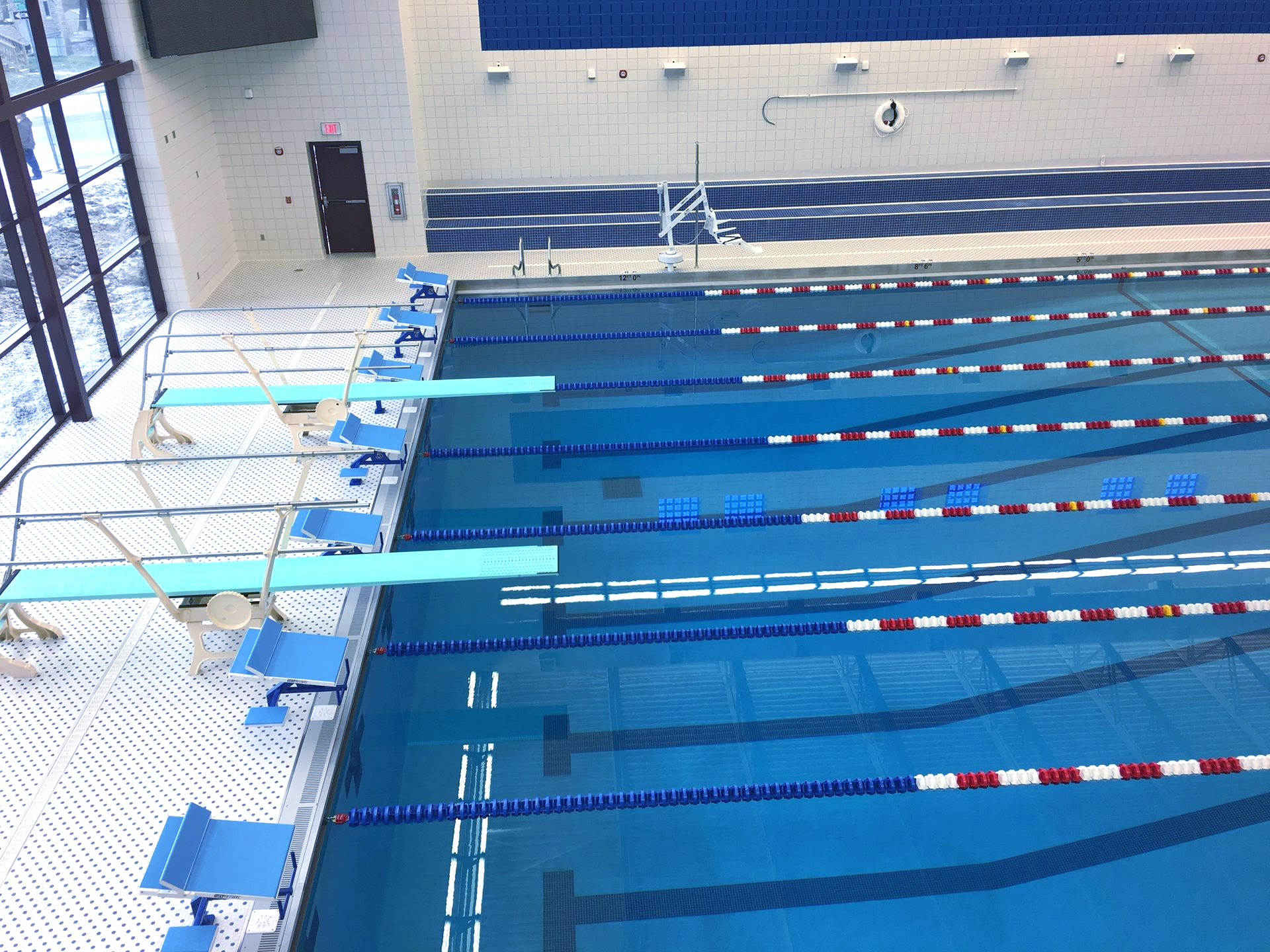 Indoor swimming pool with diving boards and lane markers.