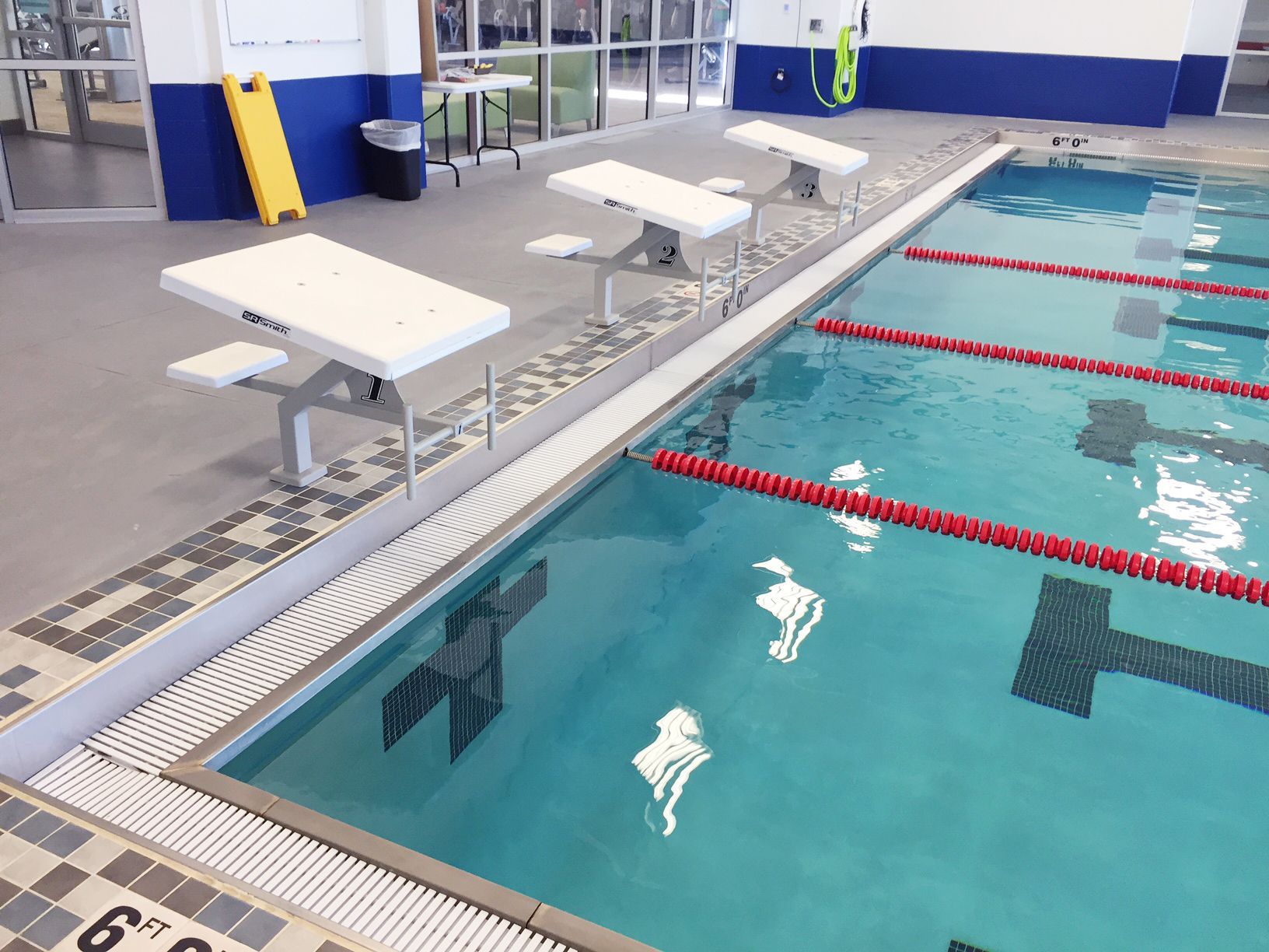 Indoor swimming pool with starting blocks and lane markers.