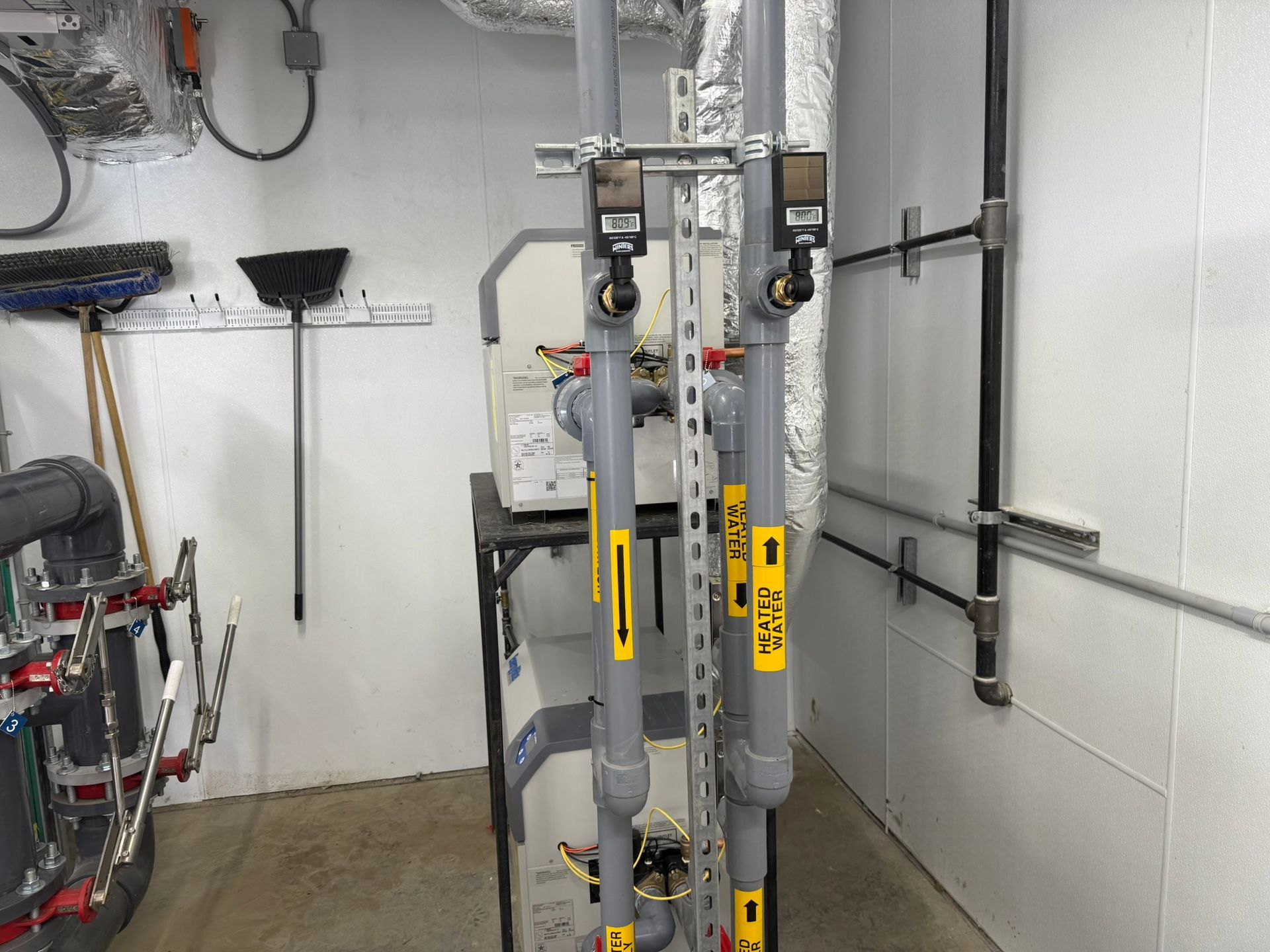 Plumbing pipes with flow meters in a utility room.