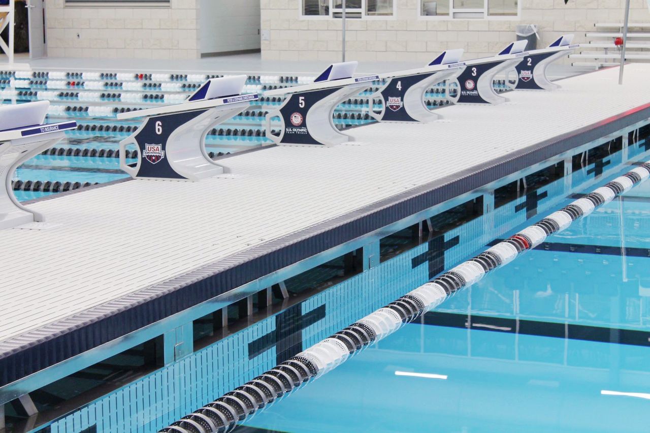 Swimming pool with numbered starting blocks, blue water, lane markers.