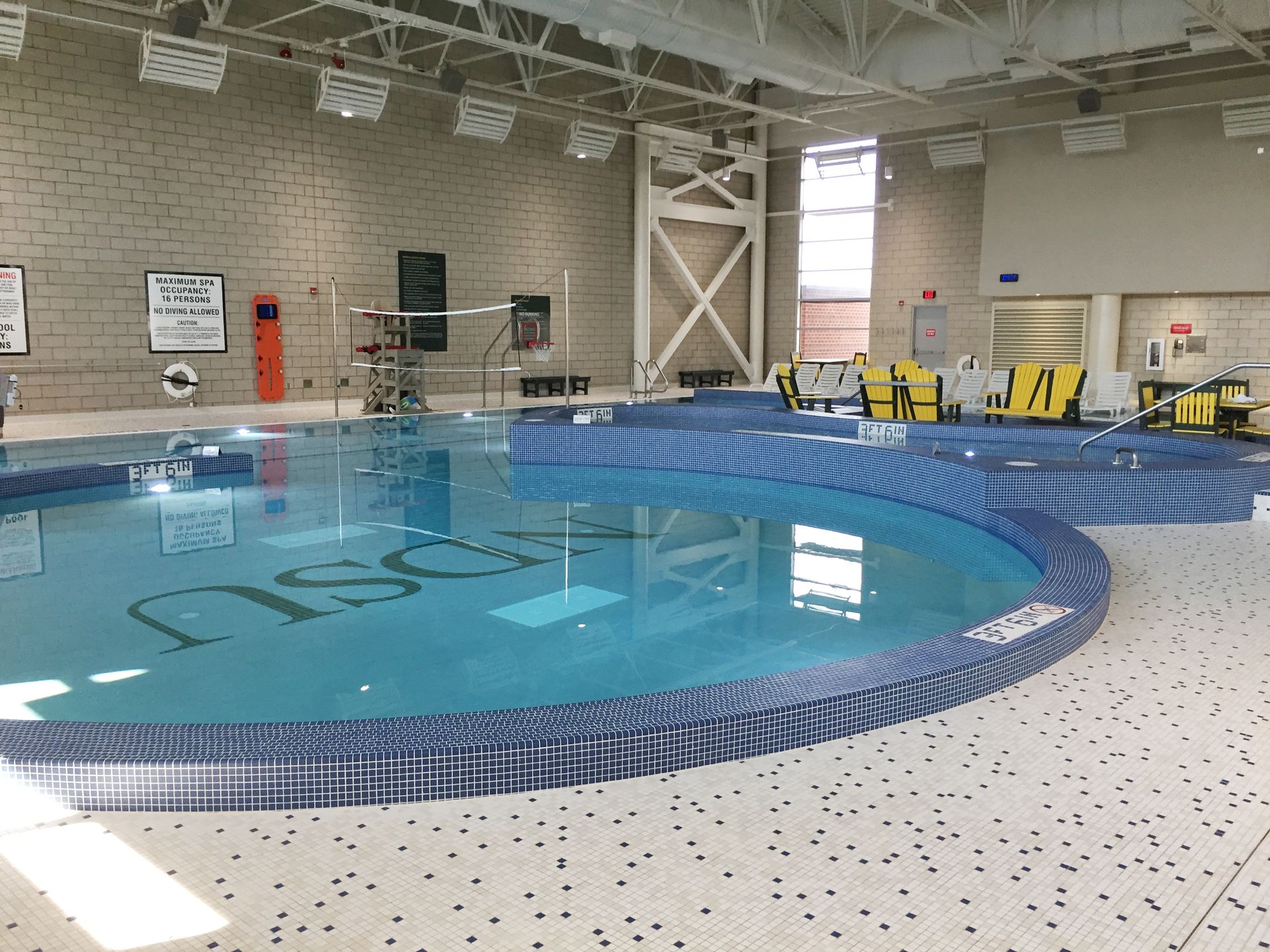 Indoor pool with blue tile, and OSU letters on the bottom. Brightly lit with equipment on deck.