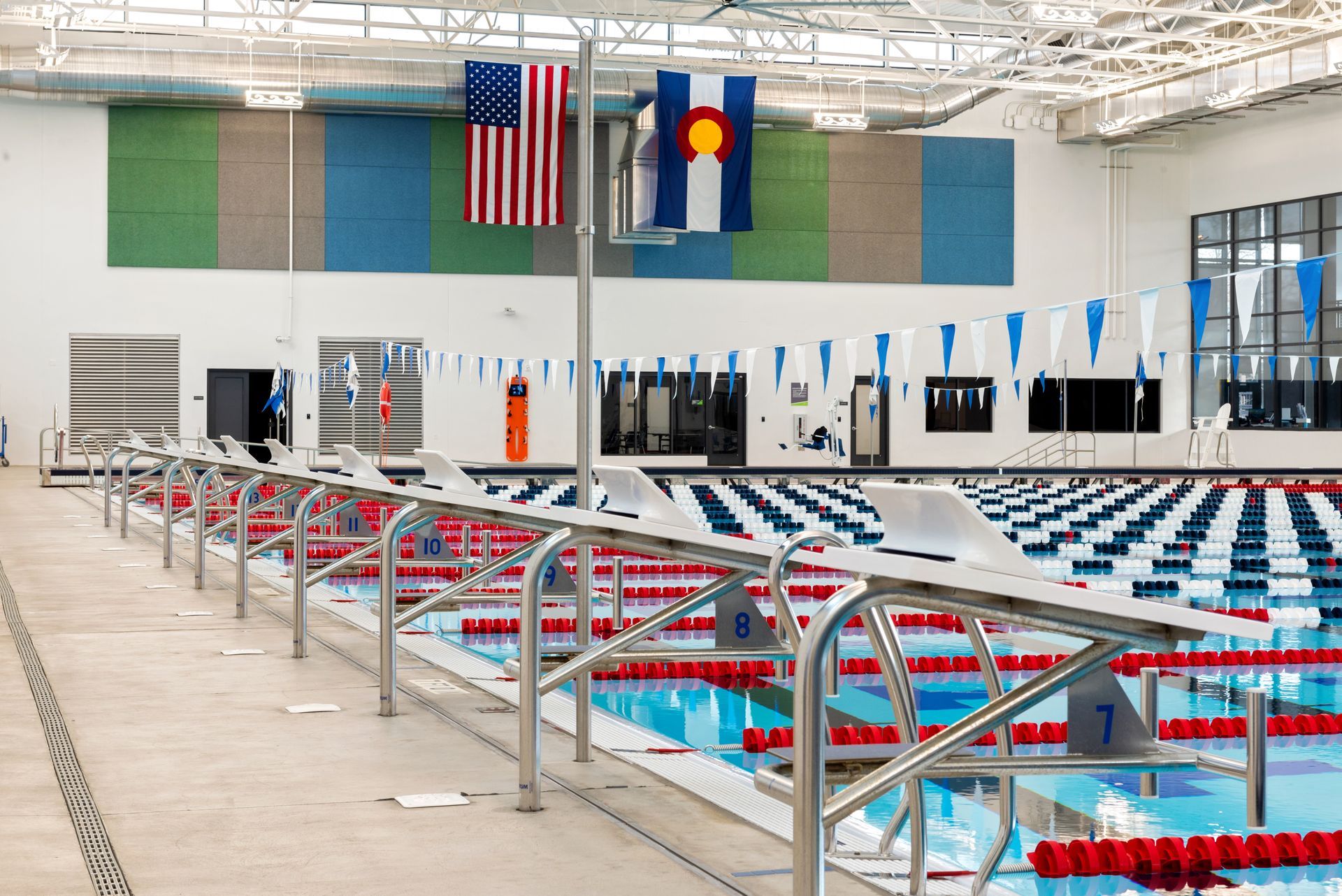 Swimming pool interior with starting blocks, lane markers, flags of the US and Colorado.