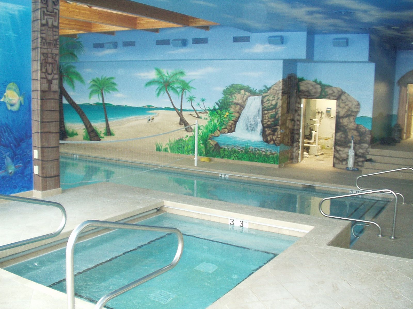 Indoor pool with a painted beach scene mural on the walls.