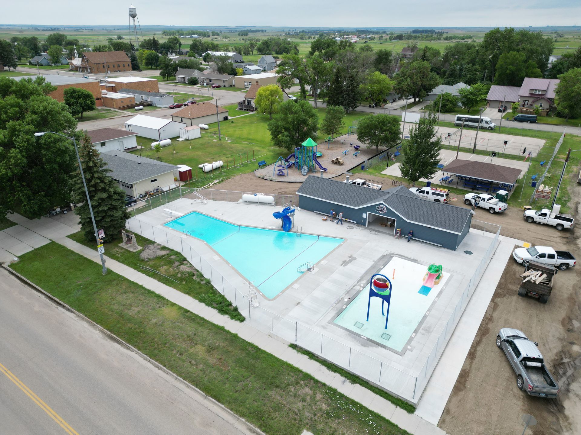 Aerial view of a community pool and playground in a small town.