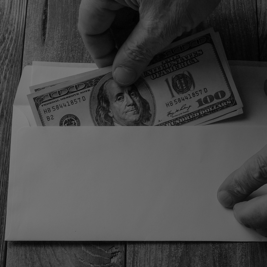 A person is putting a dollar bill in an envelope.