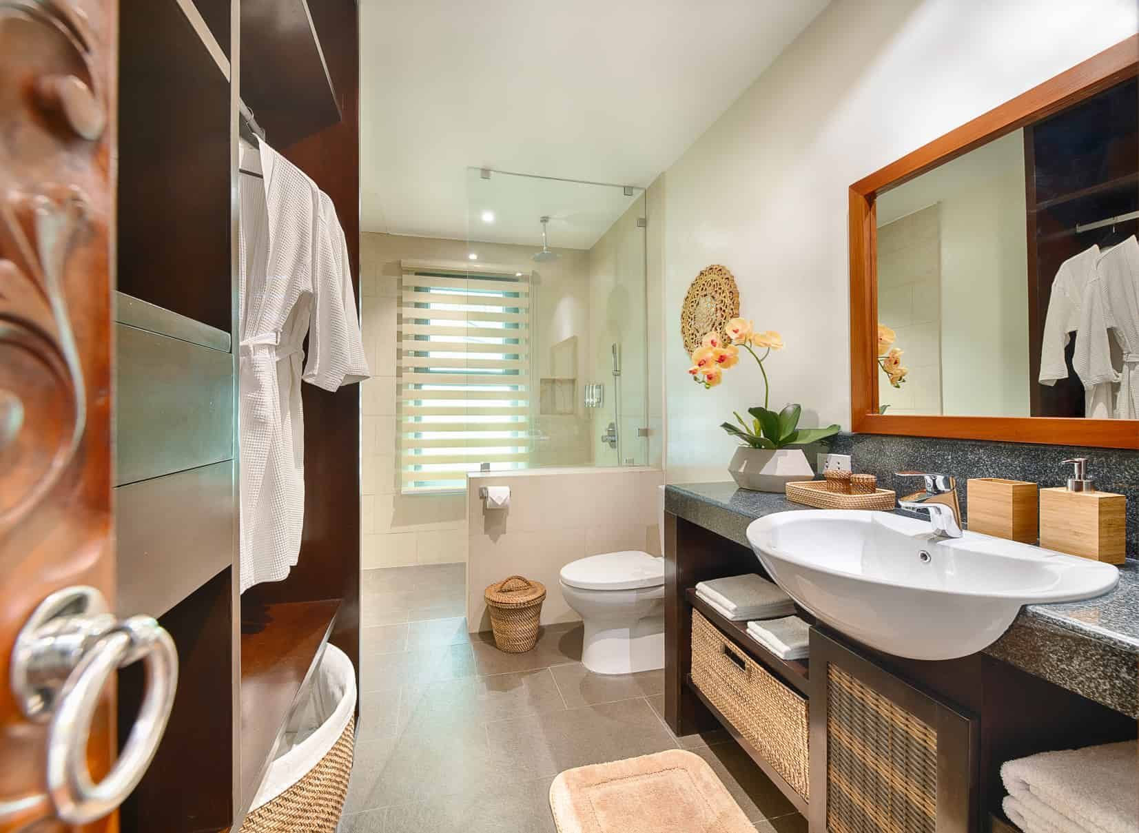 Bathroom with a sink, toilet, shower, and walk-in closet with white bathrobes.