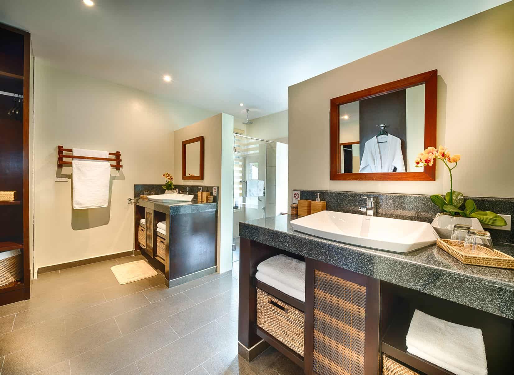 Modern bathroom with dual sinks, wooden cabinets, and a large mirror.