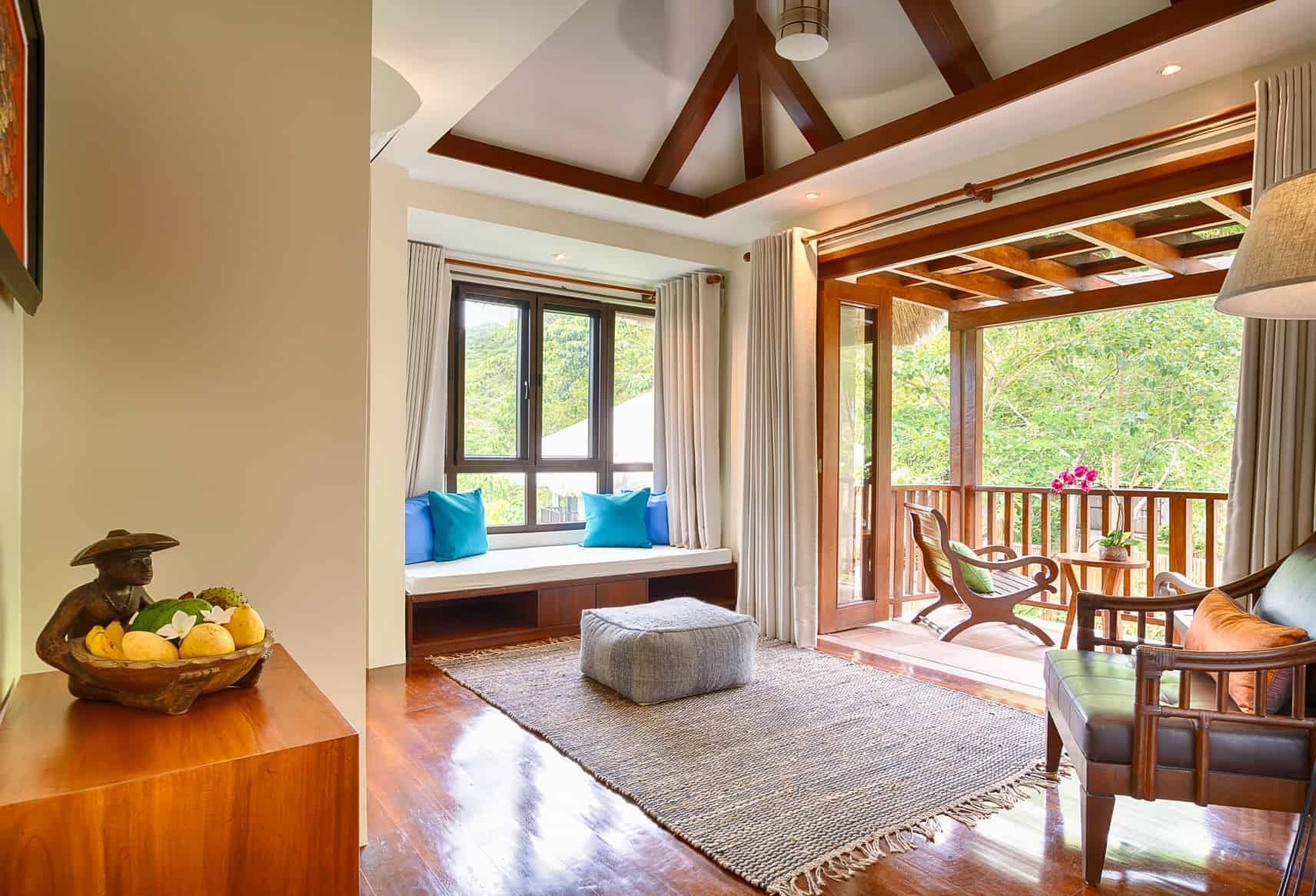 Cozy room with a wooden accent balcony, window seat with blue pillows, and wooden furniture.