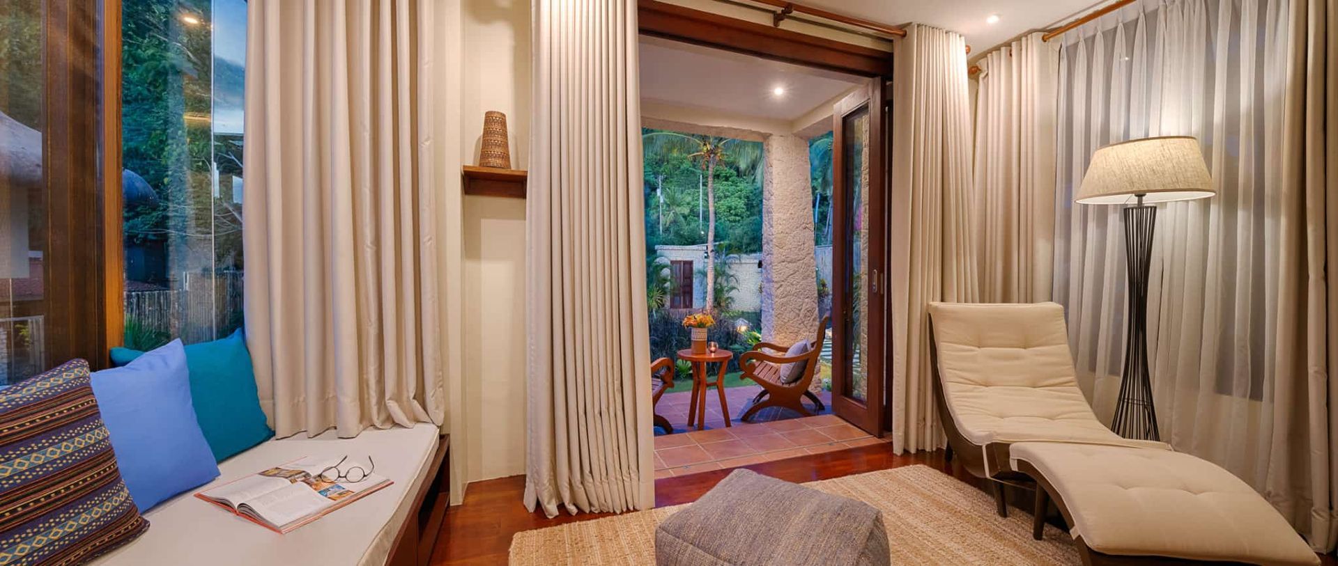 Cozy room with outdoor access. Features a chaise lounge, reading nook, and neutral-toned curtains.