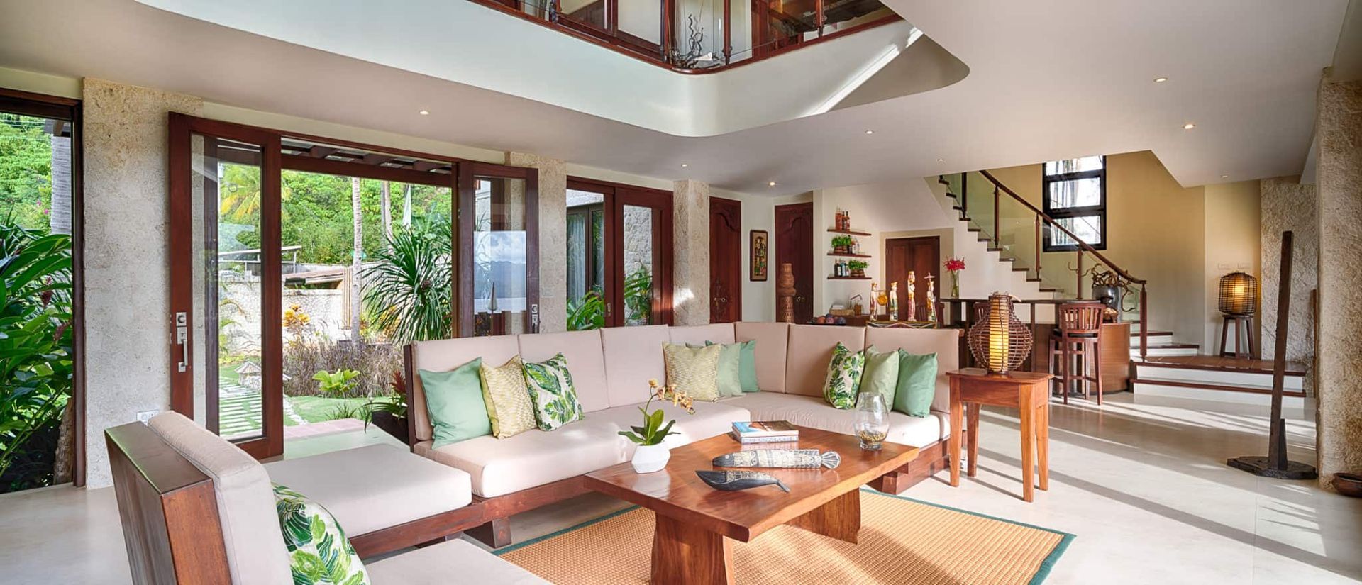 Lounge area with neutral tones, large windows, and a staircase leading to the upper level.