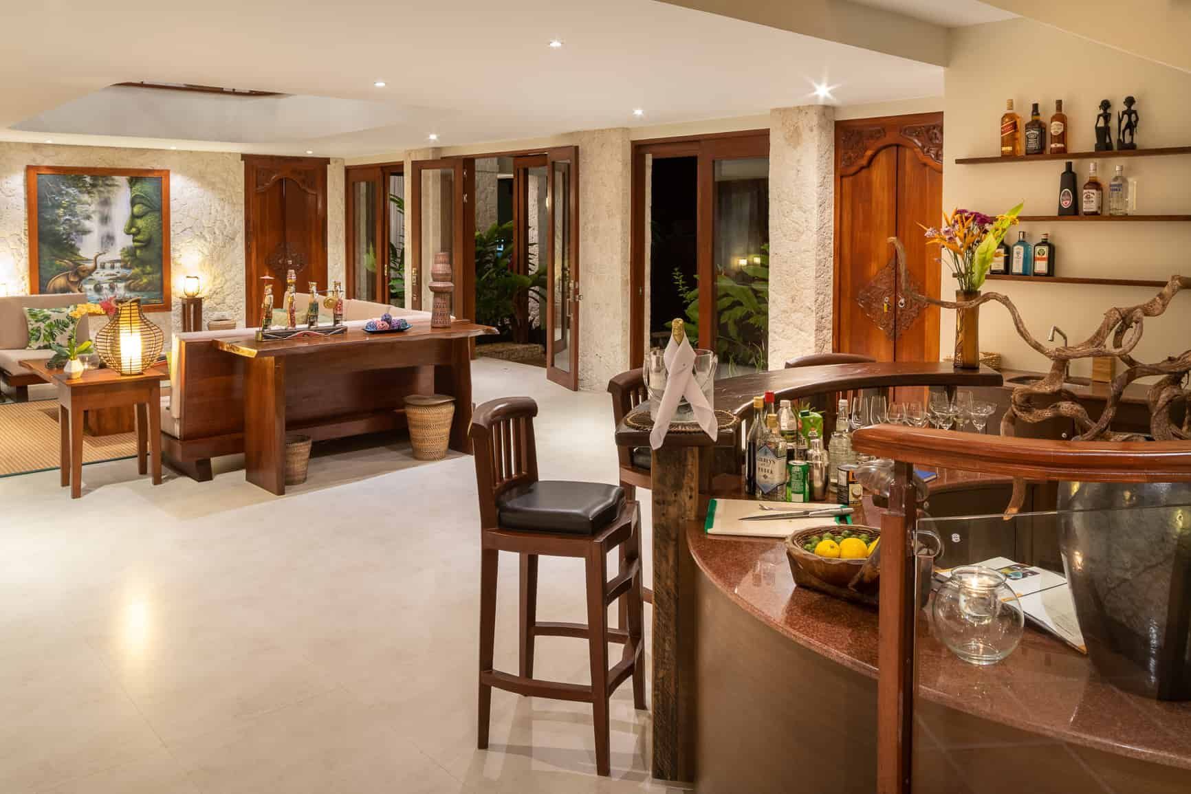 Bar area with wooden furniture, shelves of liquor, and open doors to outside.