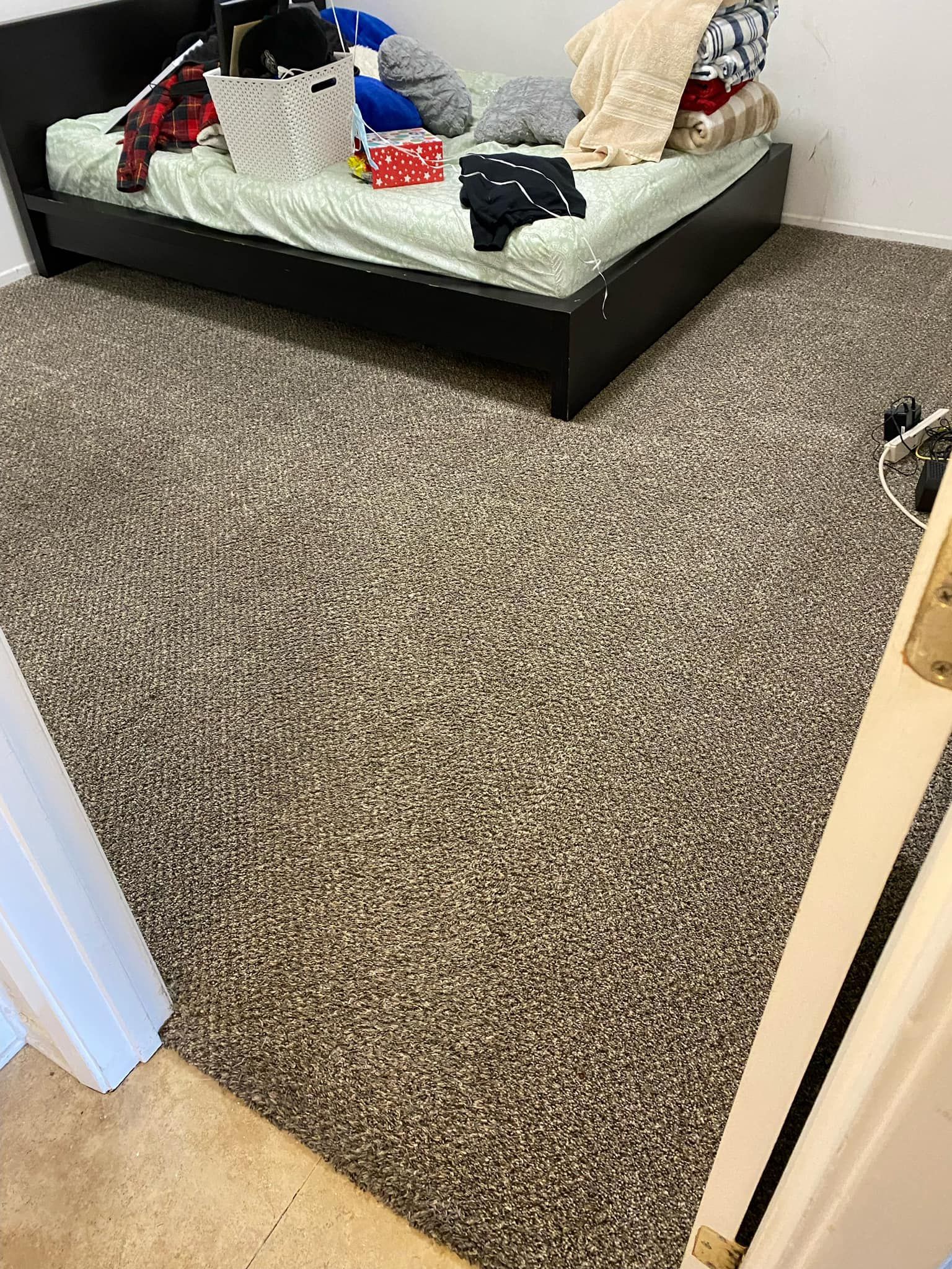 A bedroom with a bed and a carpeted floor.