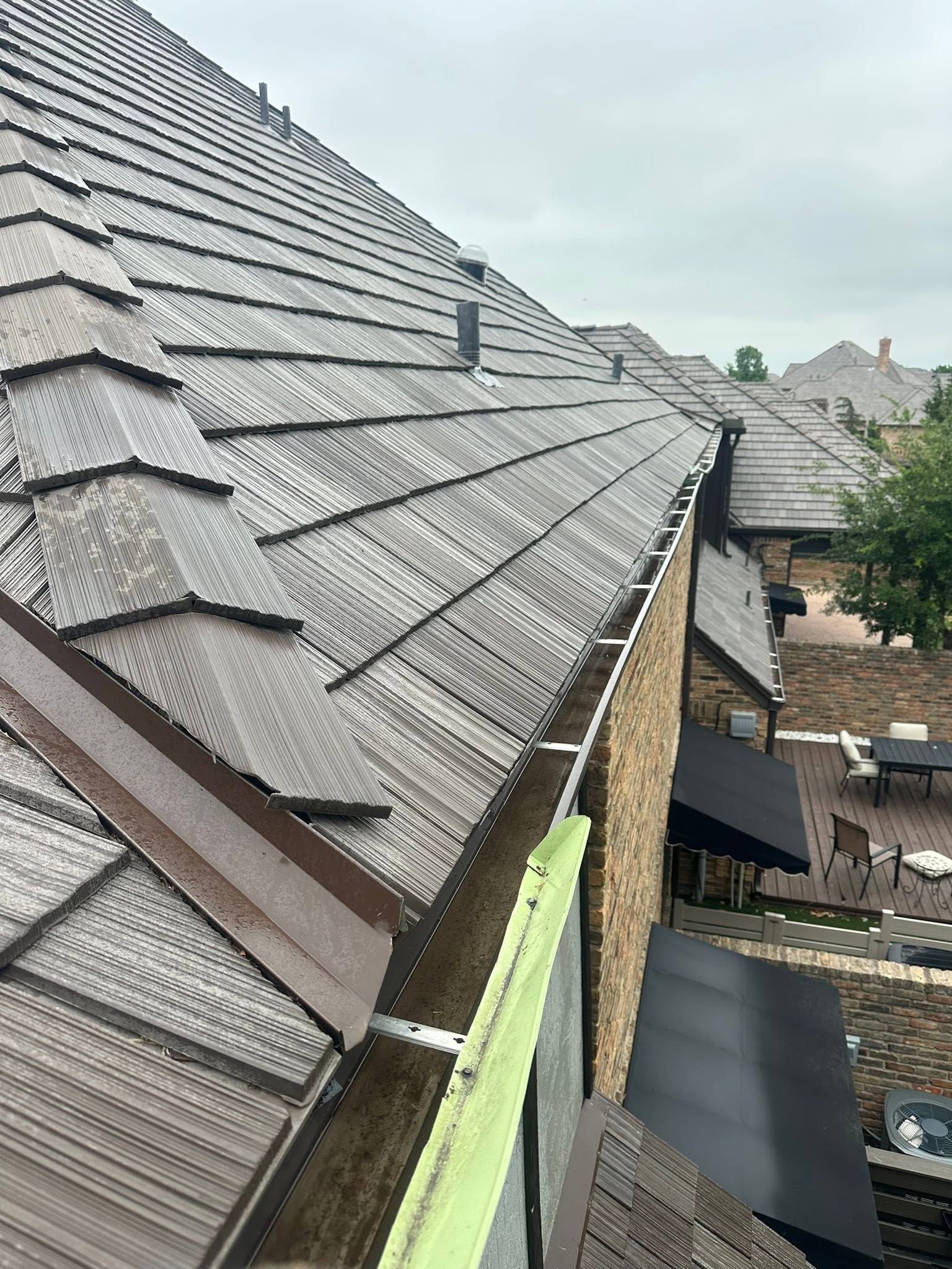 Roofing and gutters on a row of houses, with gray shingle tiles and a narrow view between buildings