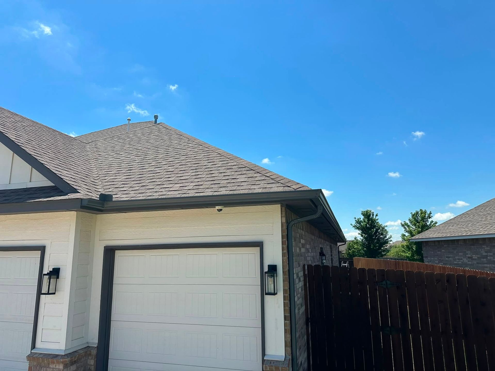 White garage and side of a house with dark fence under a blue sky