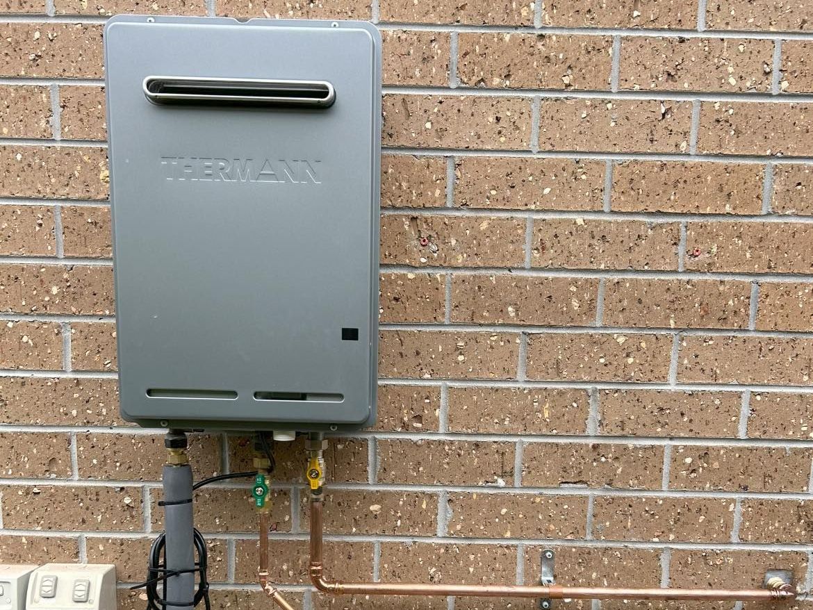 A copper shower head is attached to a brick wall