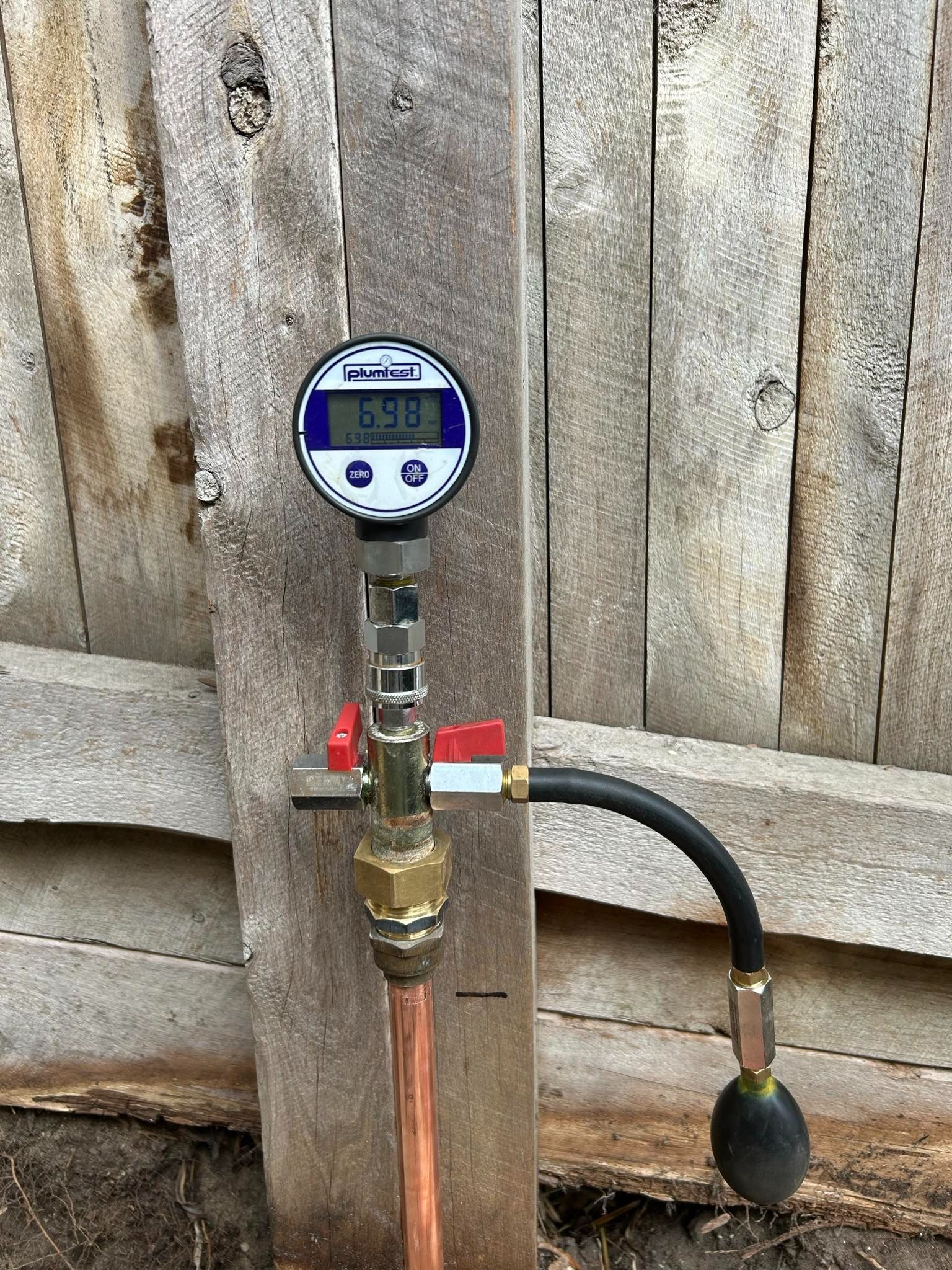 A digital pressure gauge is attached to a copper pipe.