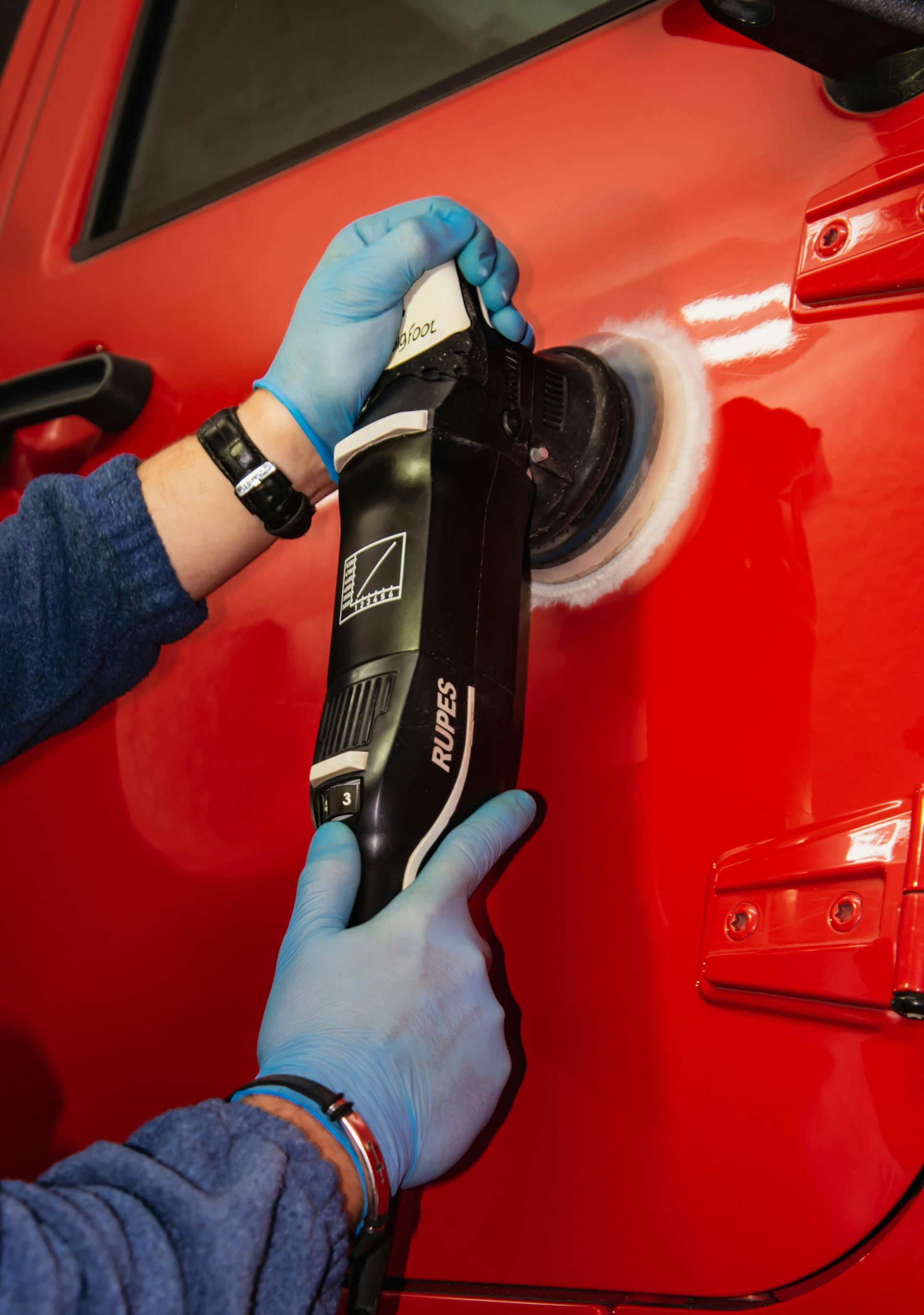 A person is polishing a red car with a machine.  | 5 Star Auto Repair