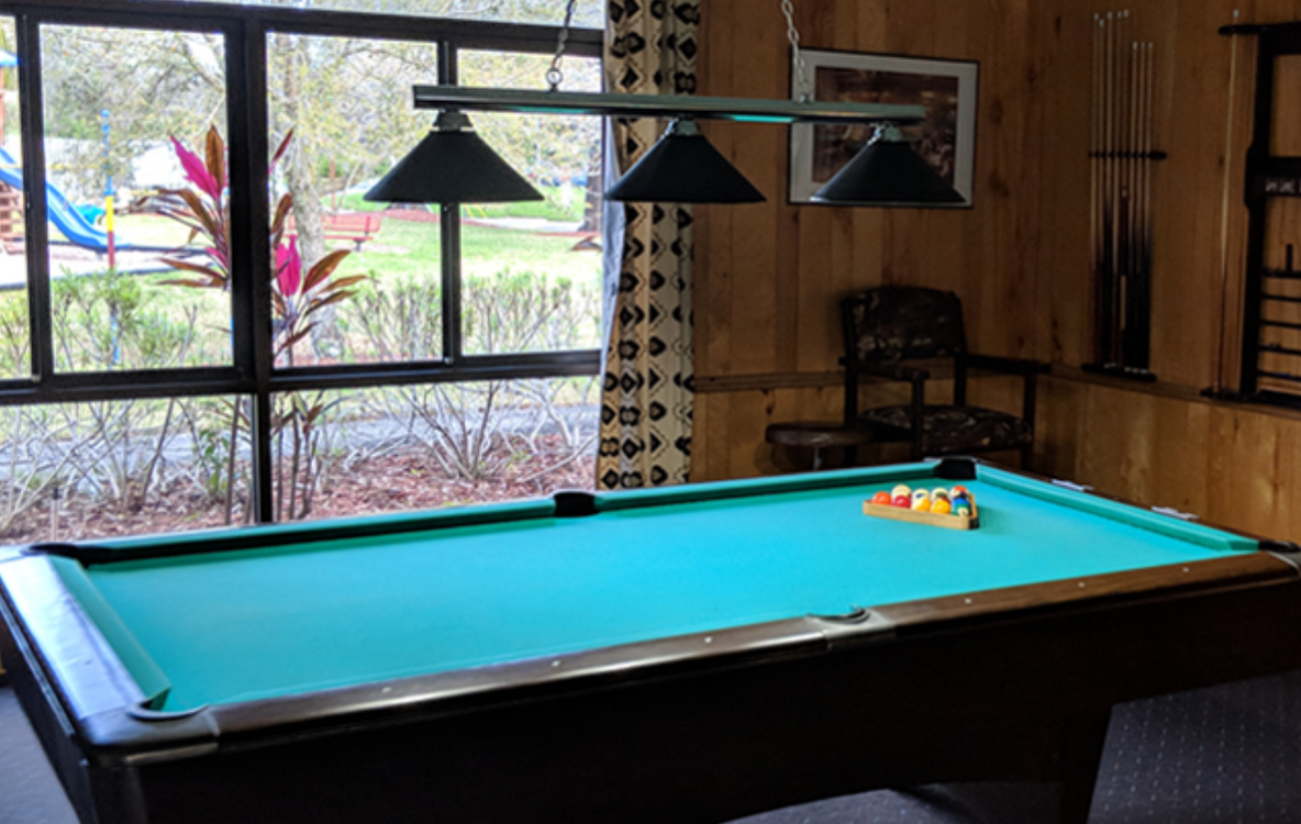 a pool table is sitting in a room next to a window