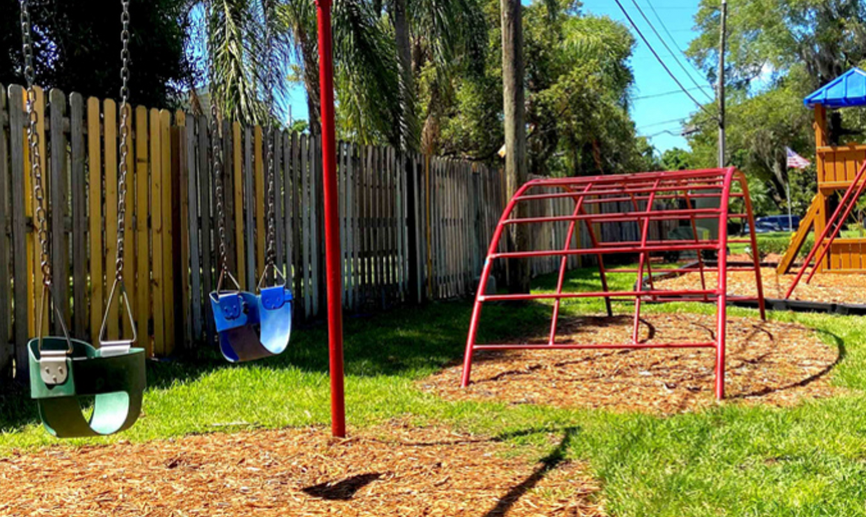 a playground with swings , a monkey bars , and a sandbox