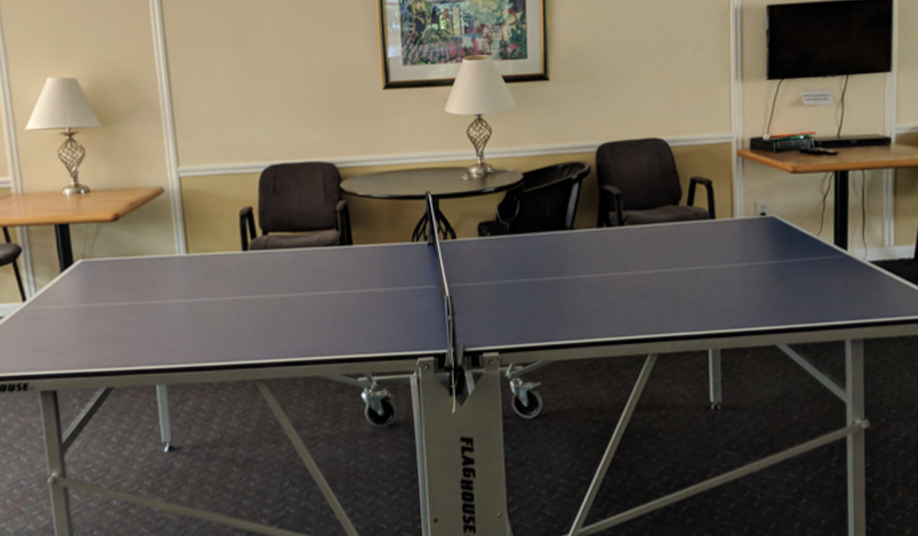 a ping pong table in a room with chairs and tables