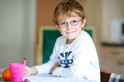 Eye-Wear — Happy School Kid Boy With Glasses at Home Making Homework  in Rockingham, NC