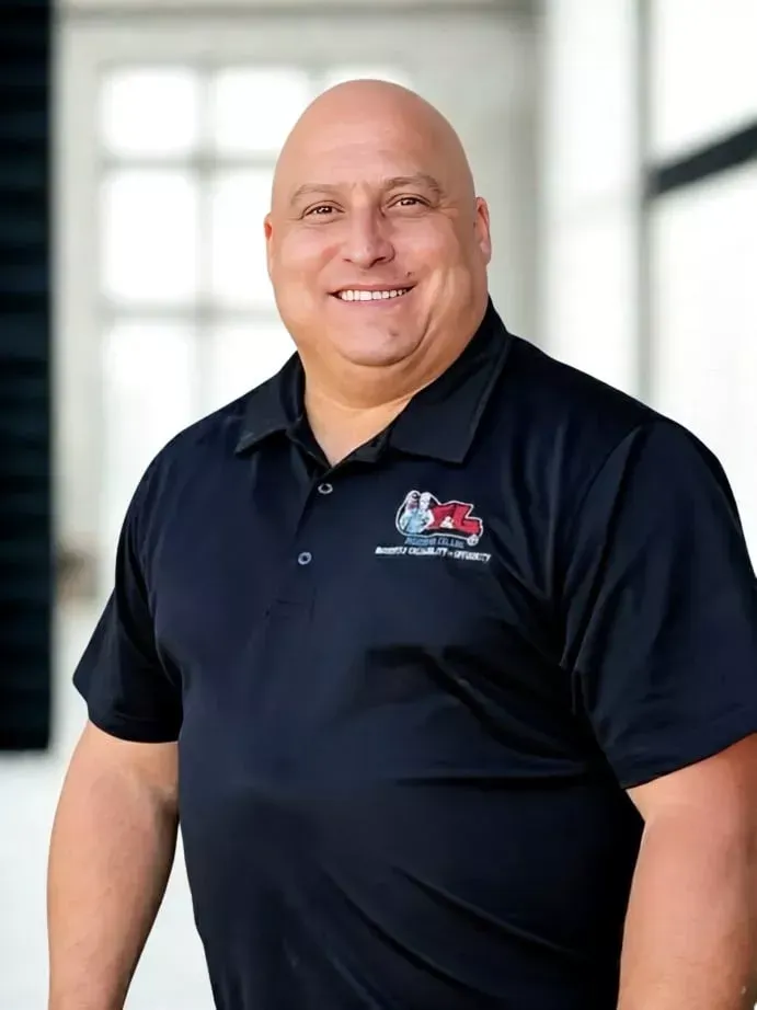 Bald man smiling, wearing black polo with logo, indoors.