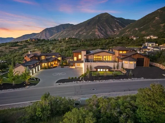 Luxury home with helipad, nestled in a mountain landscape at sunset.