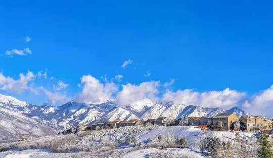 Snowy mountains and houses under a bright blue sky.