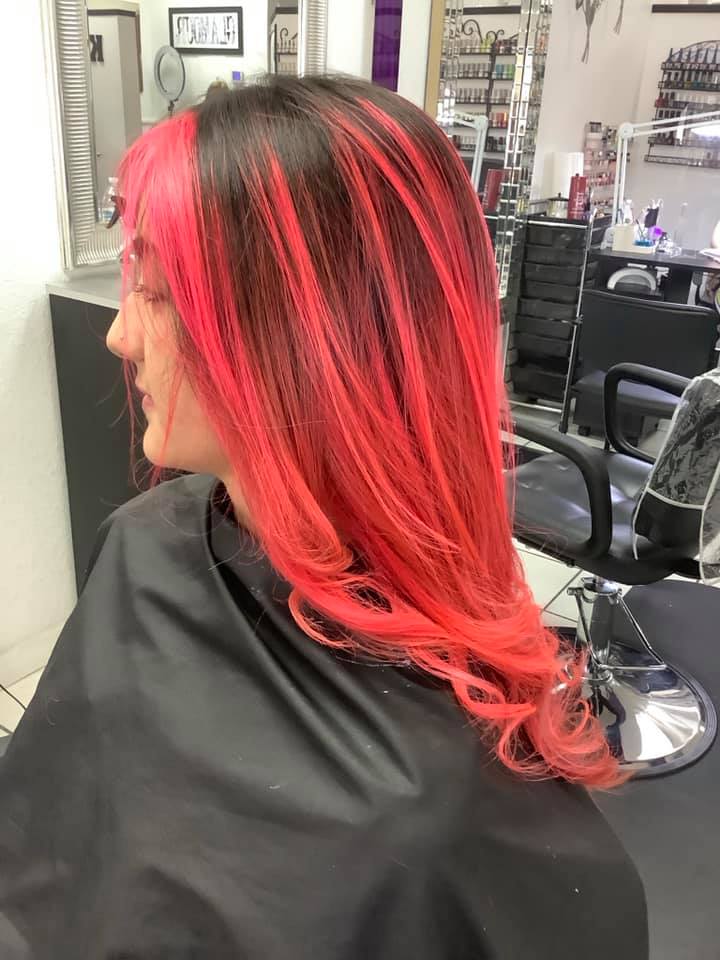 A woman with red hair is getting her hair cut in a salon.