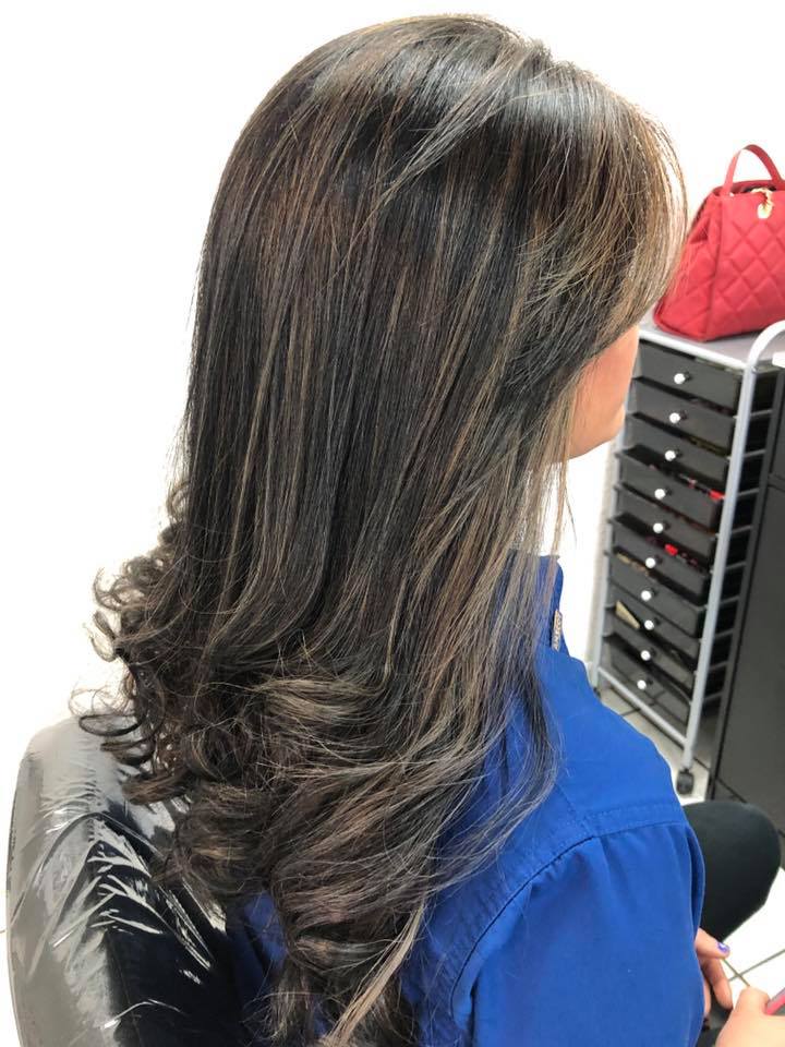 A woman with long hair is sitting in a chair in a salon.