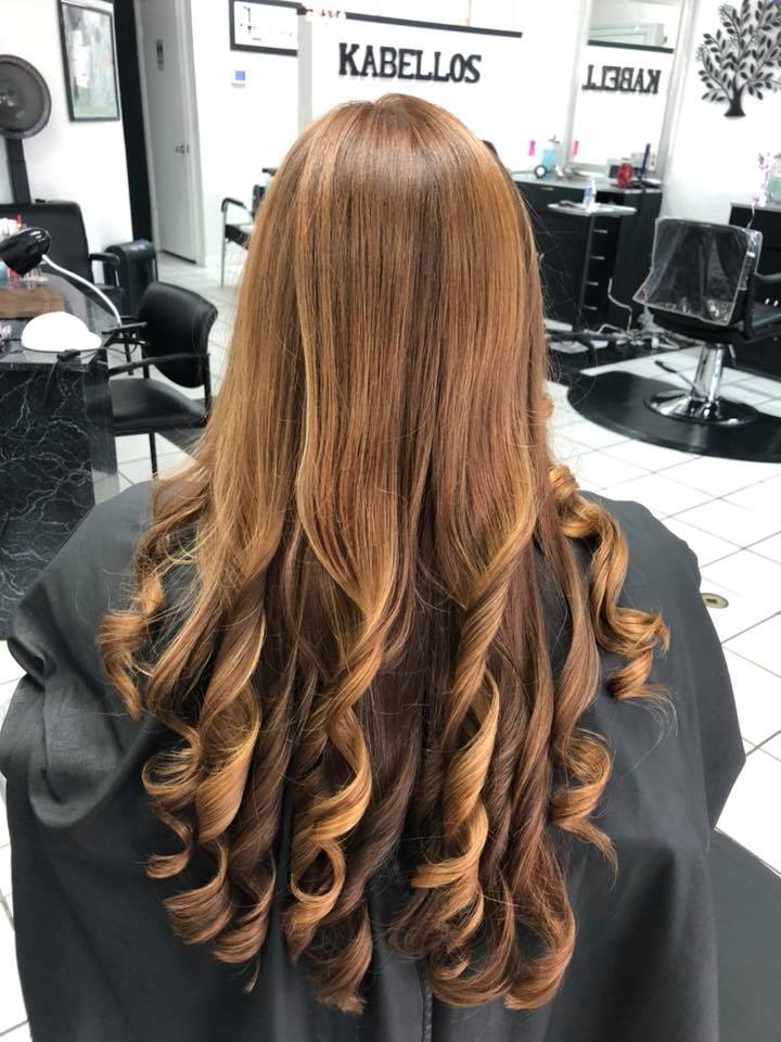 A woman with long brown hair is sitting in a chair in a hair salon.