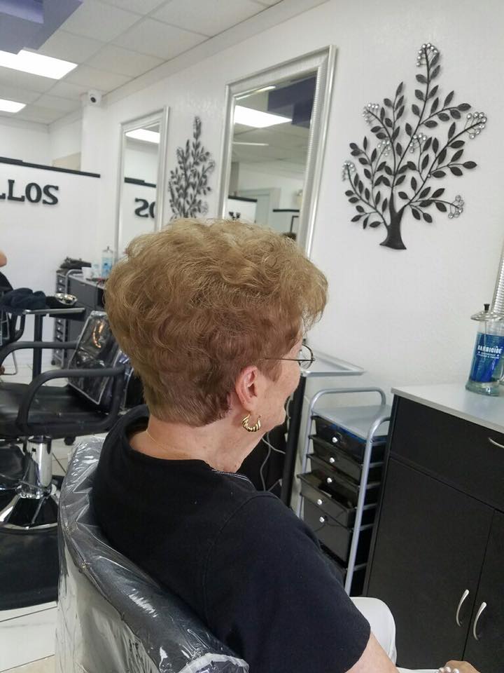 A woman is sitting in a chair at a hair salon.