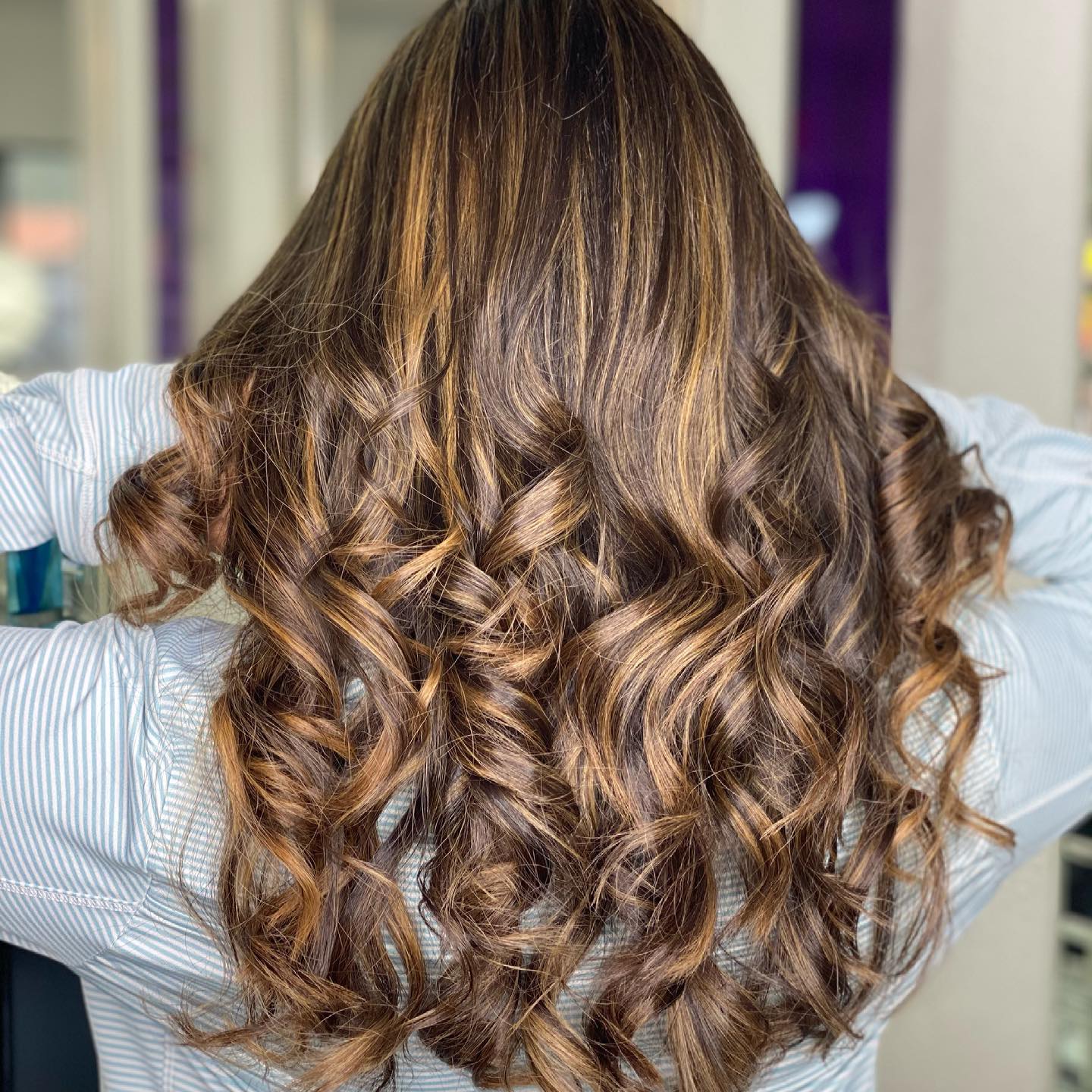 The back of a woman 's head with long curly brown hair.
