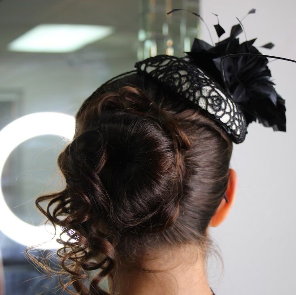 A woman 's hair is in a bun and she is wearing a black hat