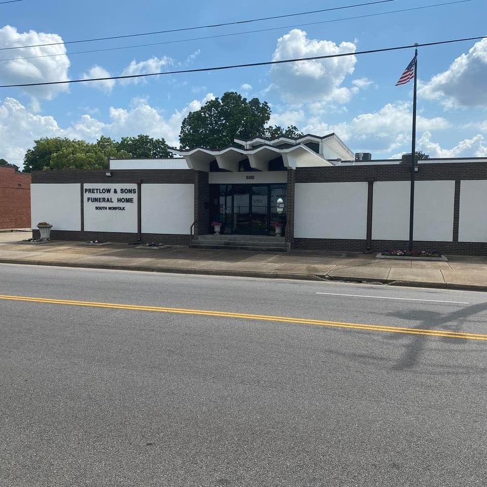Exterior of Preston & Sons Funeral Home; white building with a black sign, American flag.
