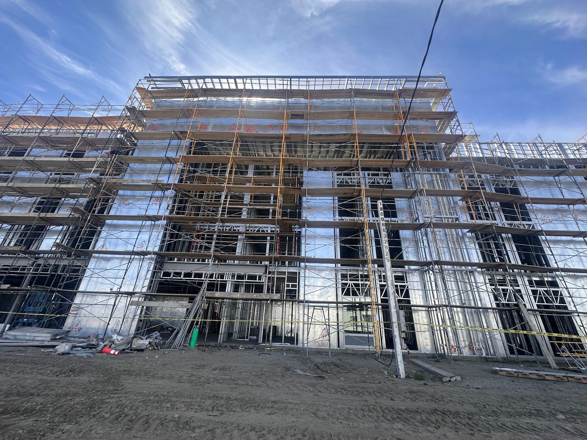 Building under construction with scaffolding, covered in reflective material, and visible burnt areas.