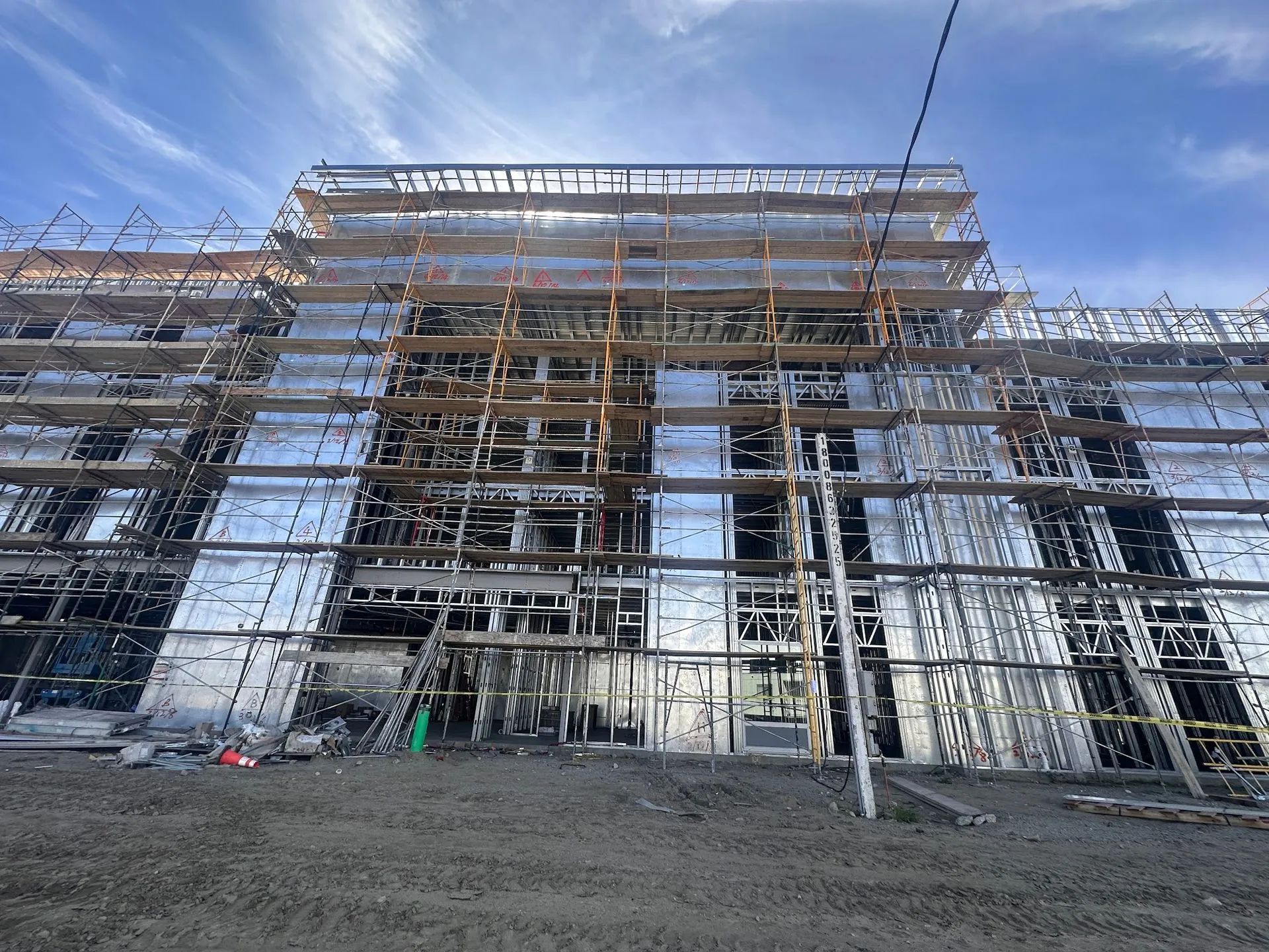 Building under construction, covered in reflective material, surrounded by scaffolding.