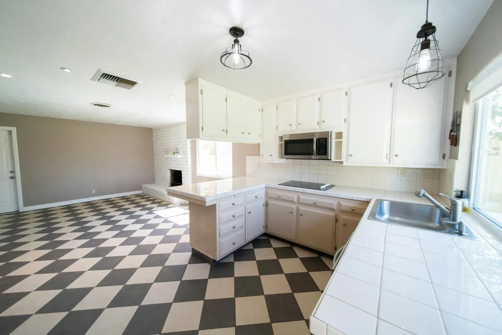 Kitchen with checkered floor, white cabinets, island, and appliances.