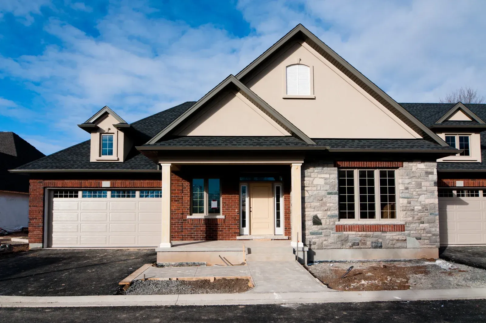 Stone patio with fire pit, pergola, and covered porch with seating, under blue sky.