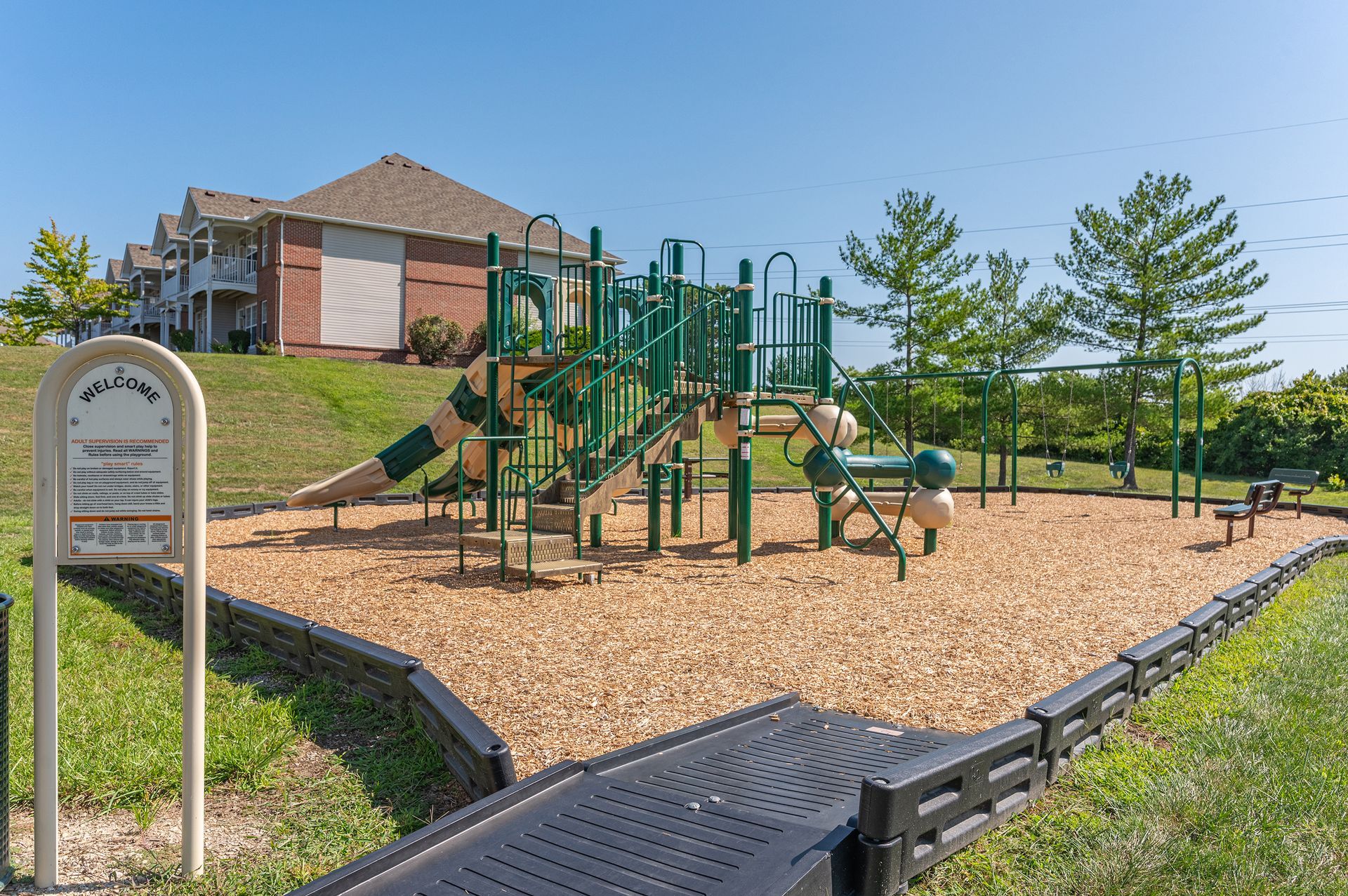 Community playground with climbing equipment and slides surrounded by mulch at Knollwood Crossing.