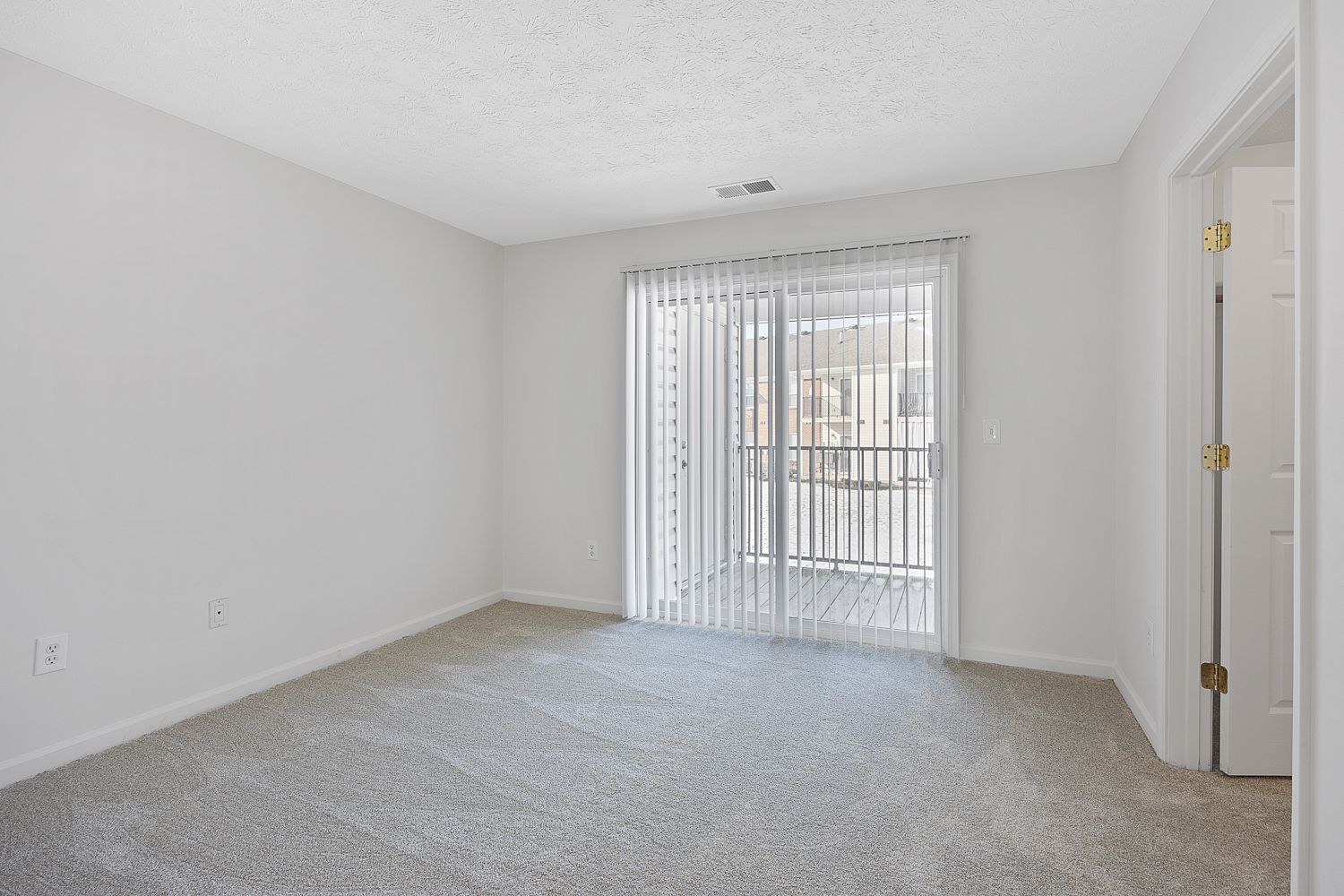 The Elm floor plan living room with carpet flooring, sliding glass doors, and neutral walls.