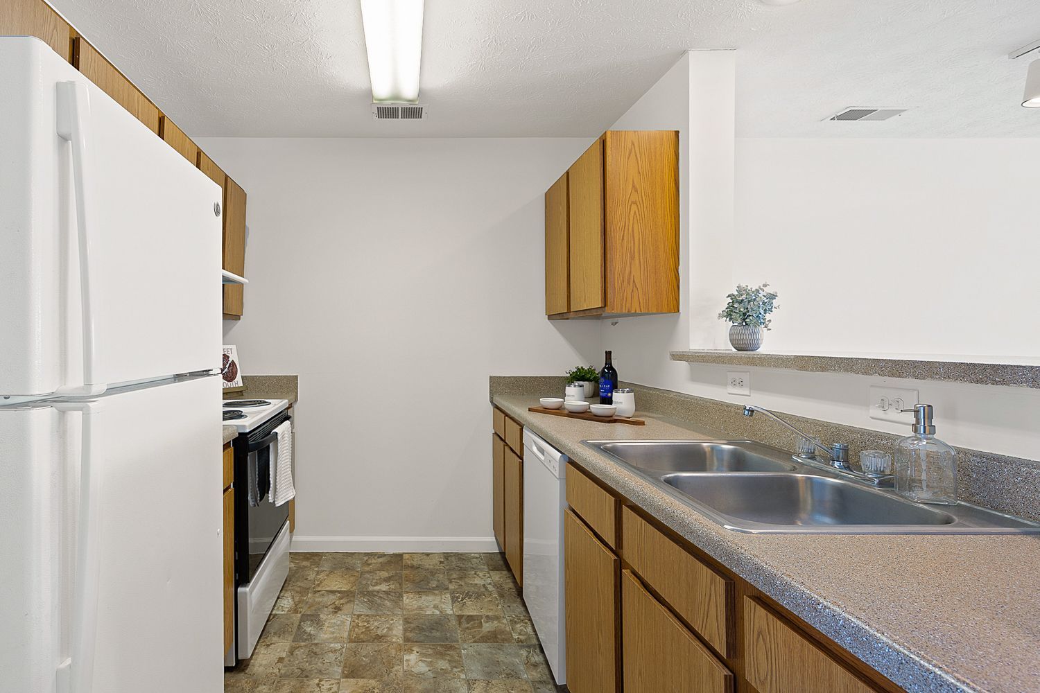 The Elm floor plan kitchen with wood cabinetry, white appliances, and double sink.