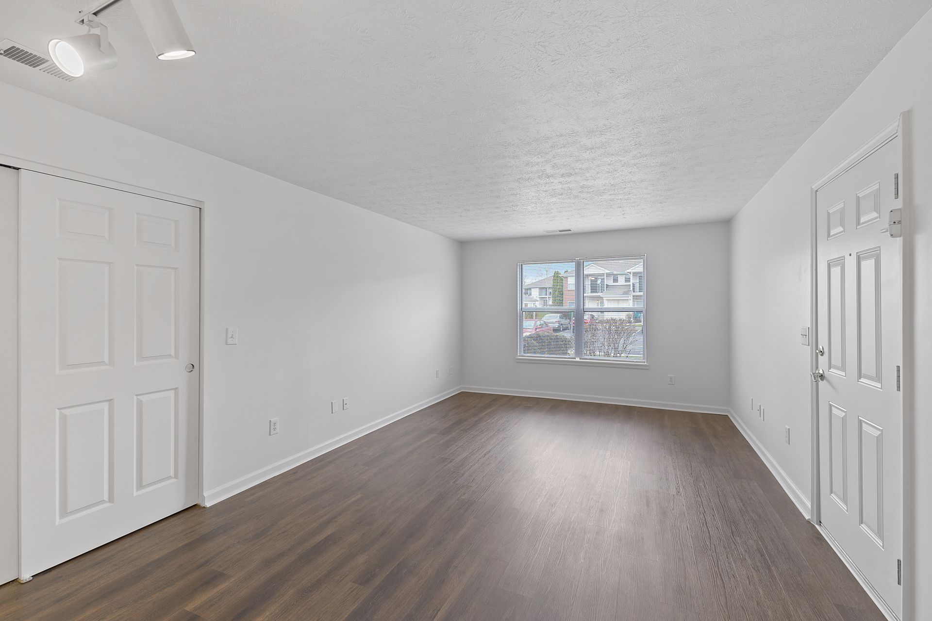 Spacious Maple floor plan living room with white walls, ceiling fan, and large window.