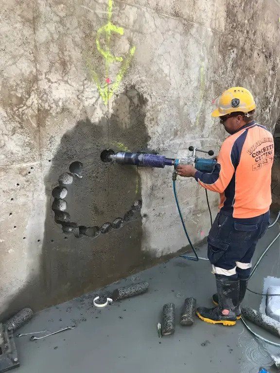 Worker Using Core Drilling Tool To The Wall — Concrete Cutting Services in Bundaberg, QLD